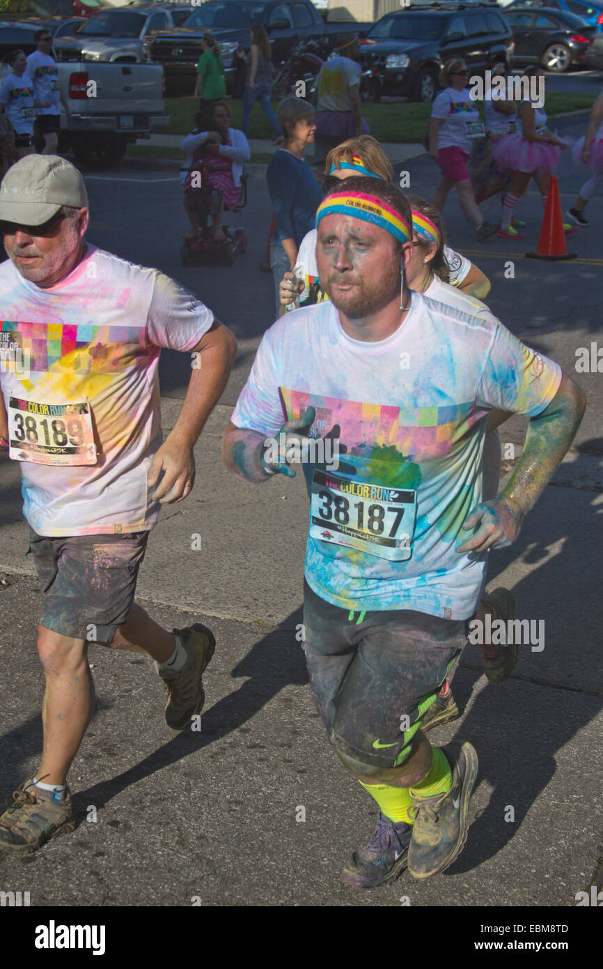 Runners splattered with colorful dye race in the the happy Asheville 5K Color Run in summer Stock Photo