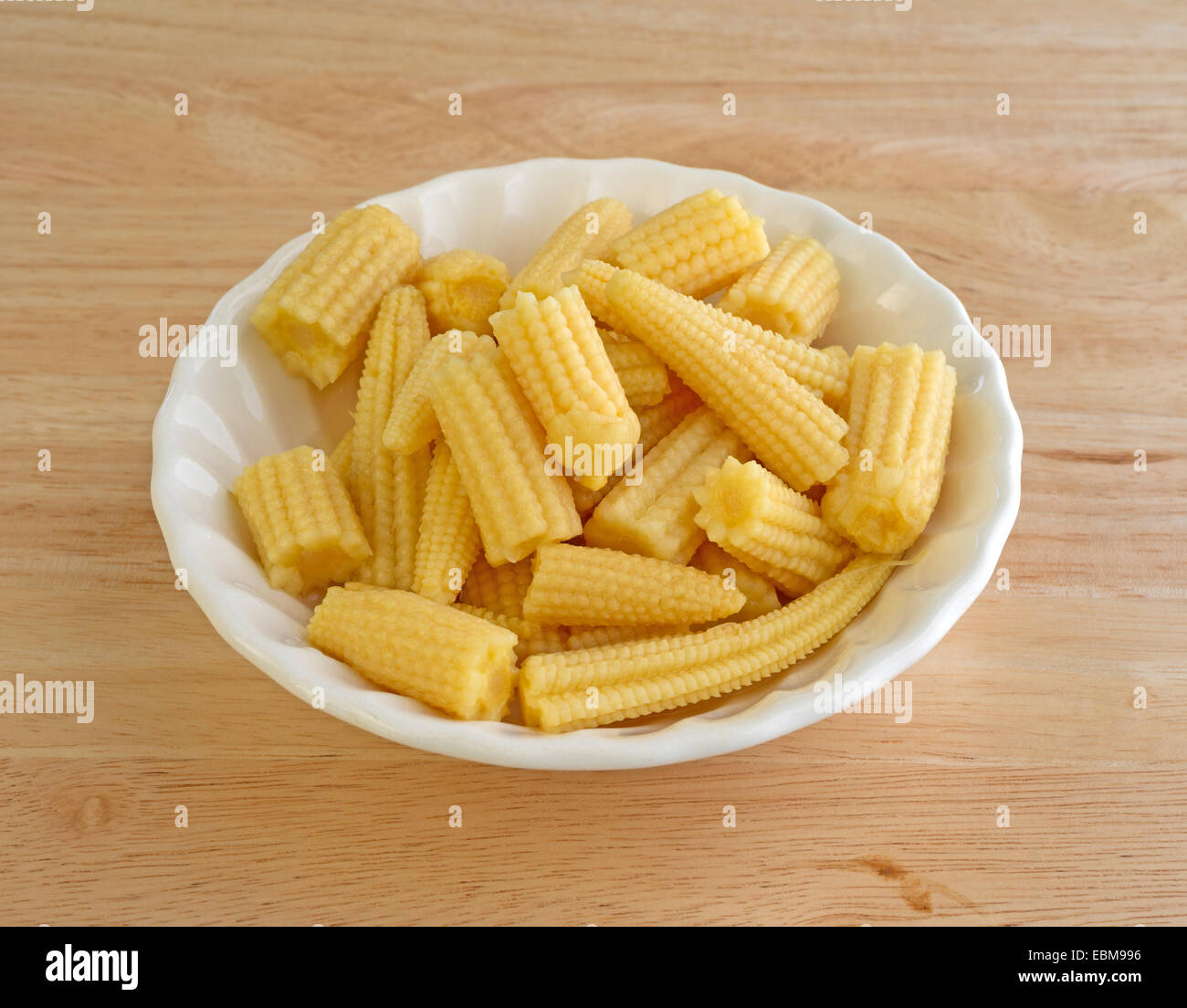 A small bowl of corn nuggets atop a wood table. Stock Photo
