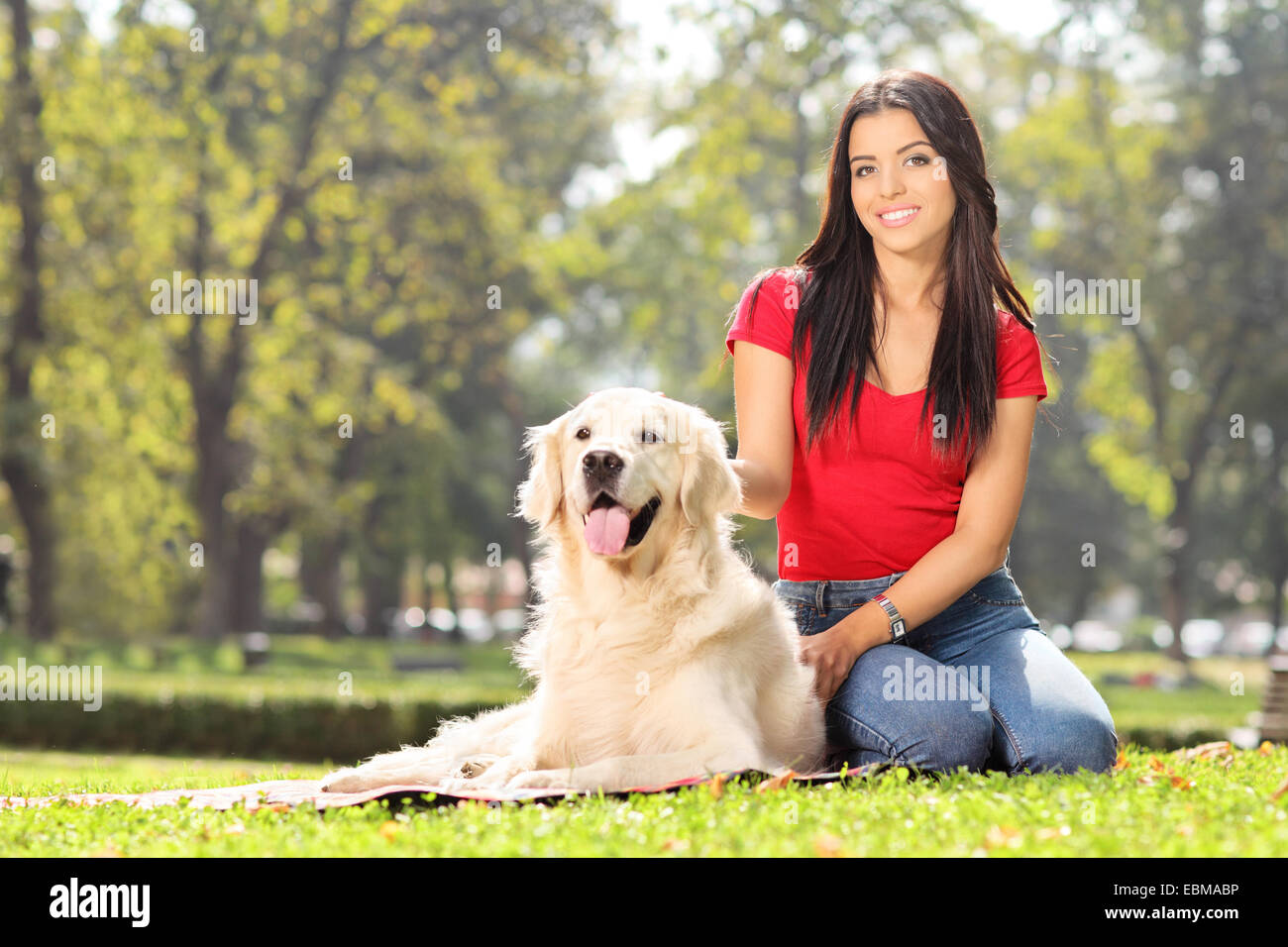 Girl sitting in park with her pet dog Stock Photo