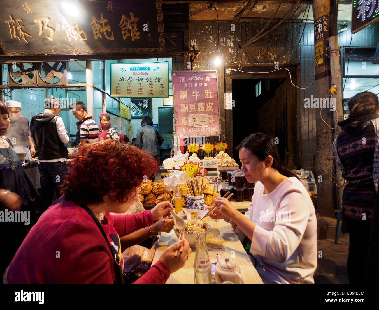People eating with chopsticks on the streets of the Muslim quarter in