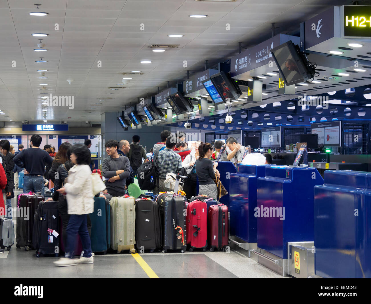 Passengers with luggage waiting in line at the check in counter at Beijing Capital International Airport, China Stock Photo