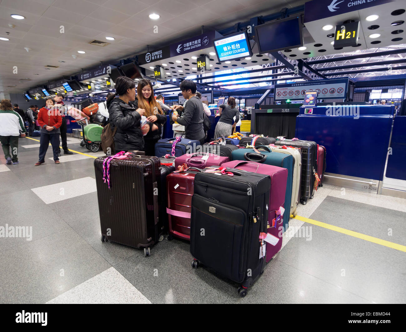 Passengers with luggage waiting in line at the check in counter at Beijing Capital International Airport, China Stock Photo