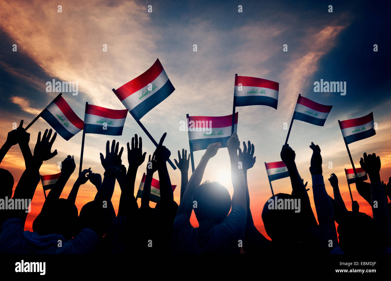 Silhouettes of People Waving the Flag of Iraq Stock Photo