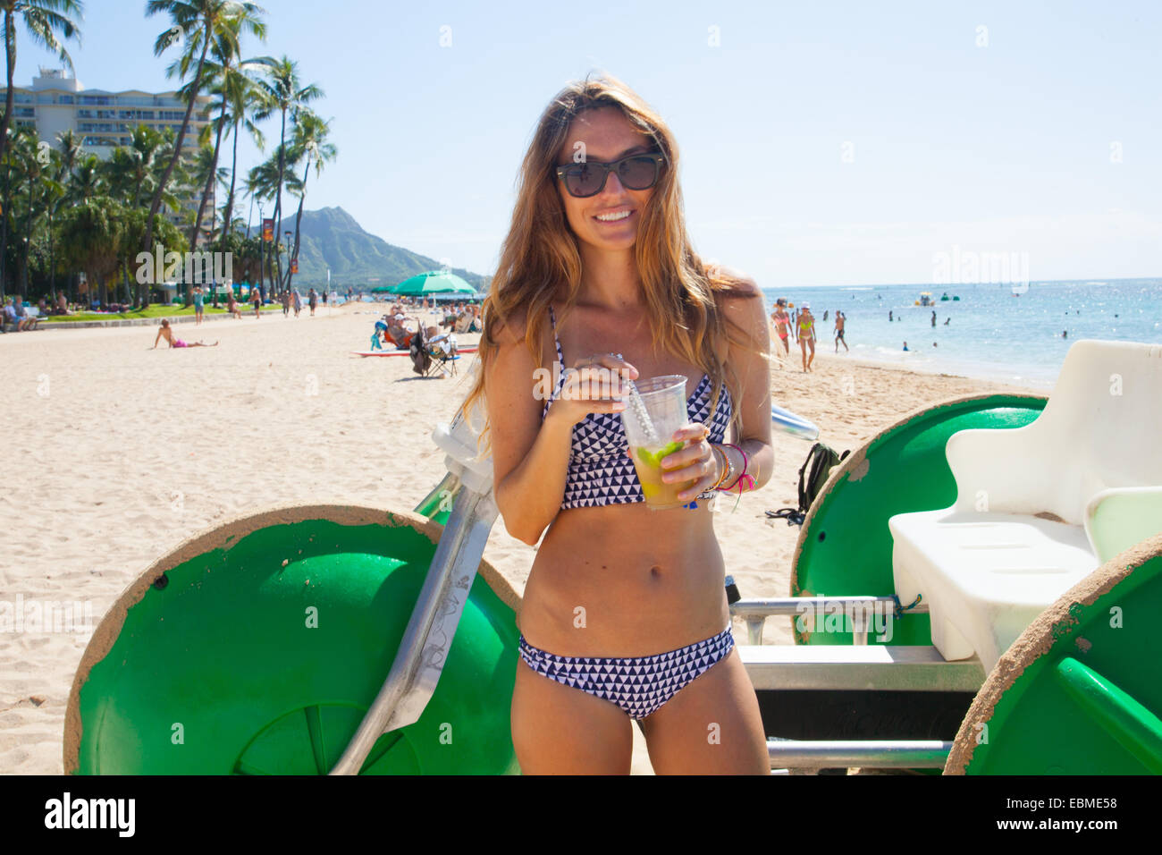 Woman in bikini in Waikiki Hawaii standing near aqua bike Stock Photo