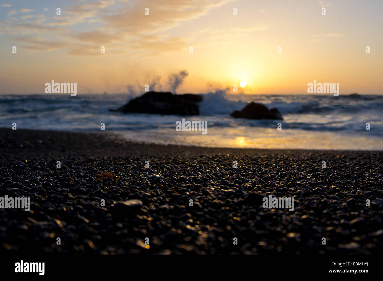 Abstract blurred ocean shore and romantic sunset. Focus on illuminated pebbles. Shallow depth of field. Lanzarote, Canary Island Stock Photo
