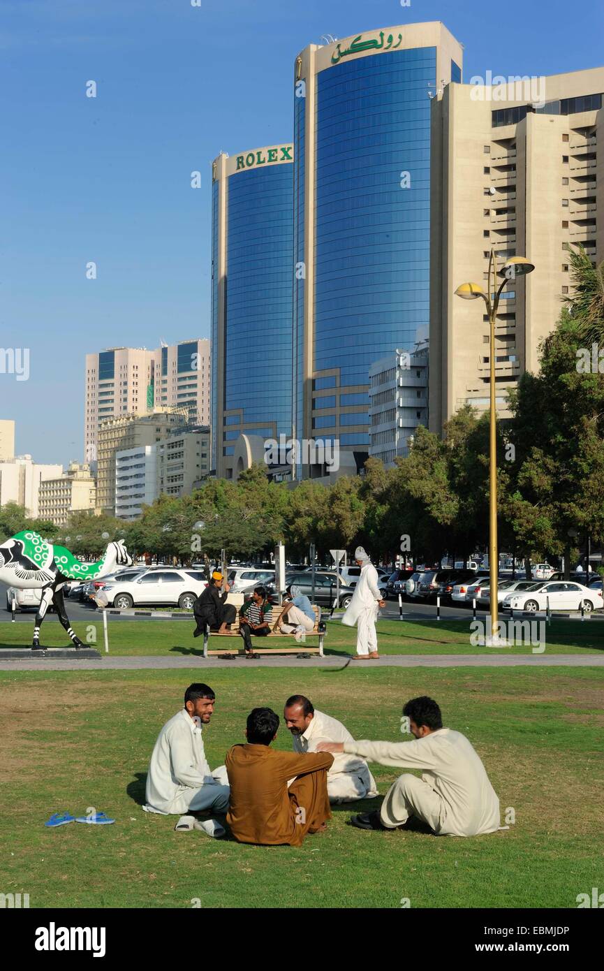 Locals in a park in front of the Rolex Towers, Daira, Dubai, Emirate of Dubai, United Arab Emirates Stock Photo
