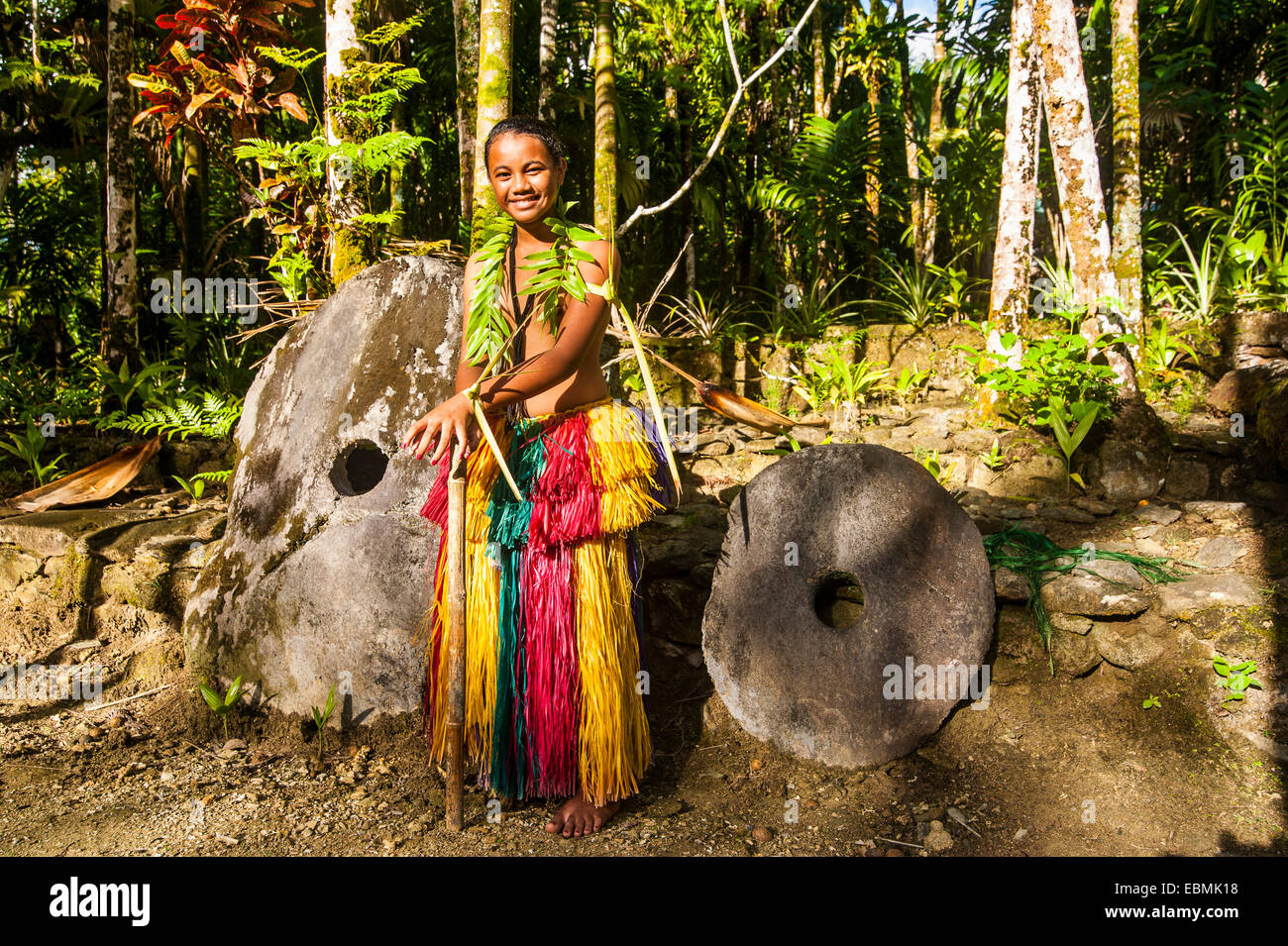 Traditionally dressed girl standing in front of stone money, Yap Island, Caroline Islands, Micronesia Stock Photo