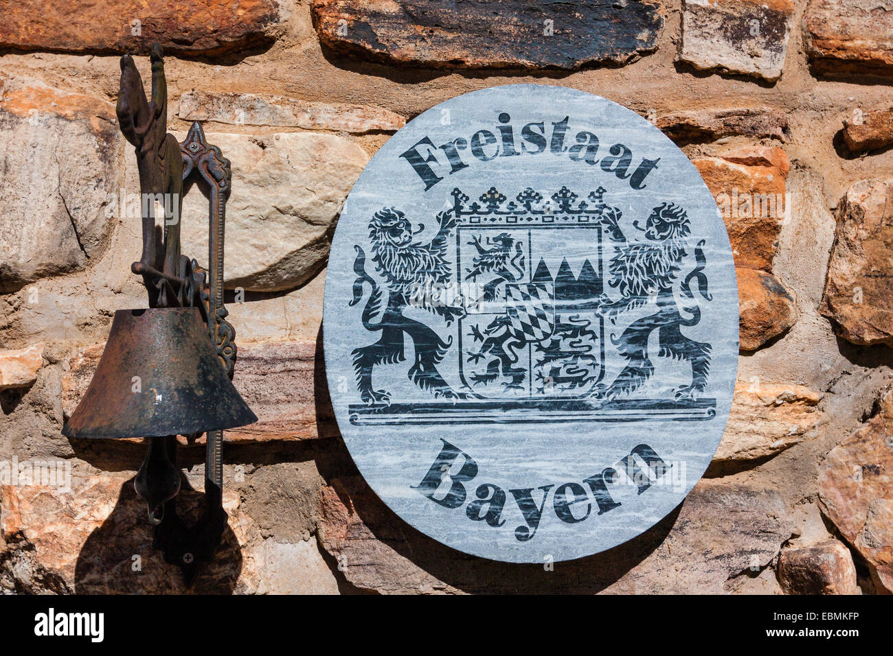 Sign 'Freistaat Bayern', English for 'Free State of Bavaria' with a bell on a natural stone wall, Namibia Stock Photo