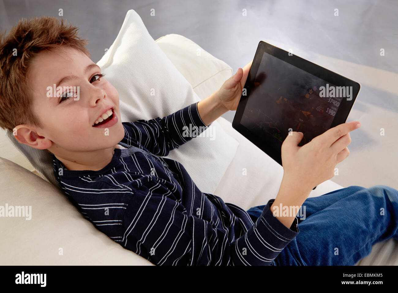 Boy sitting with tablet pc on a sofa, Germany Stock Photo