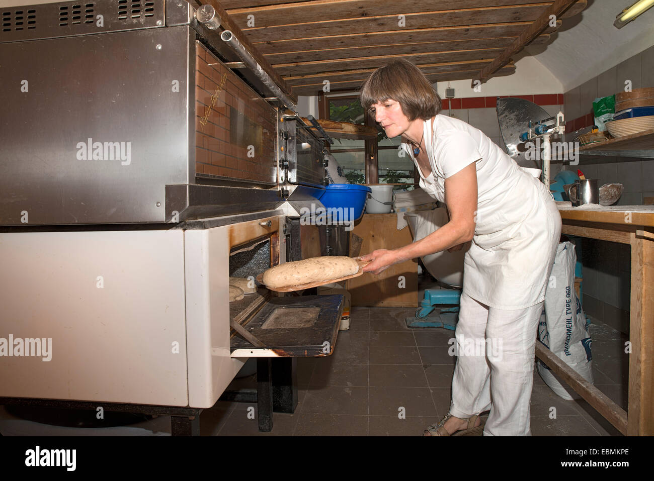 Farmer making bread in her own bakery at the farm, feeding the oven, Tyrol, Austria Stock Photo