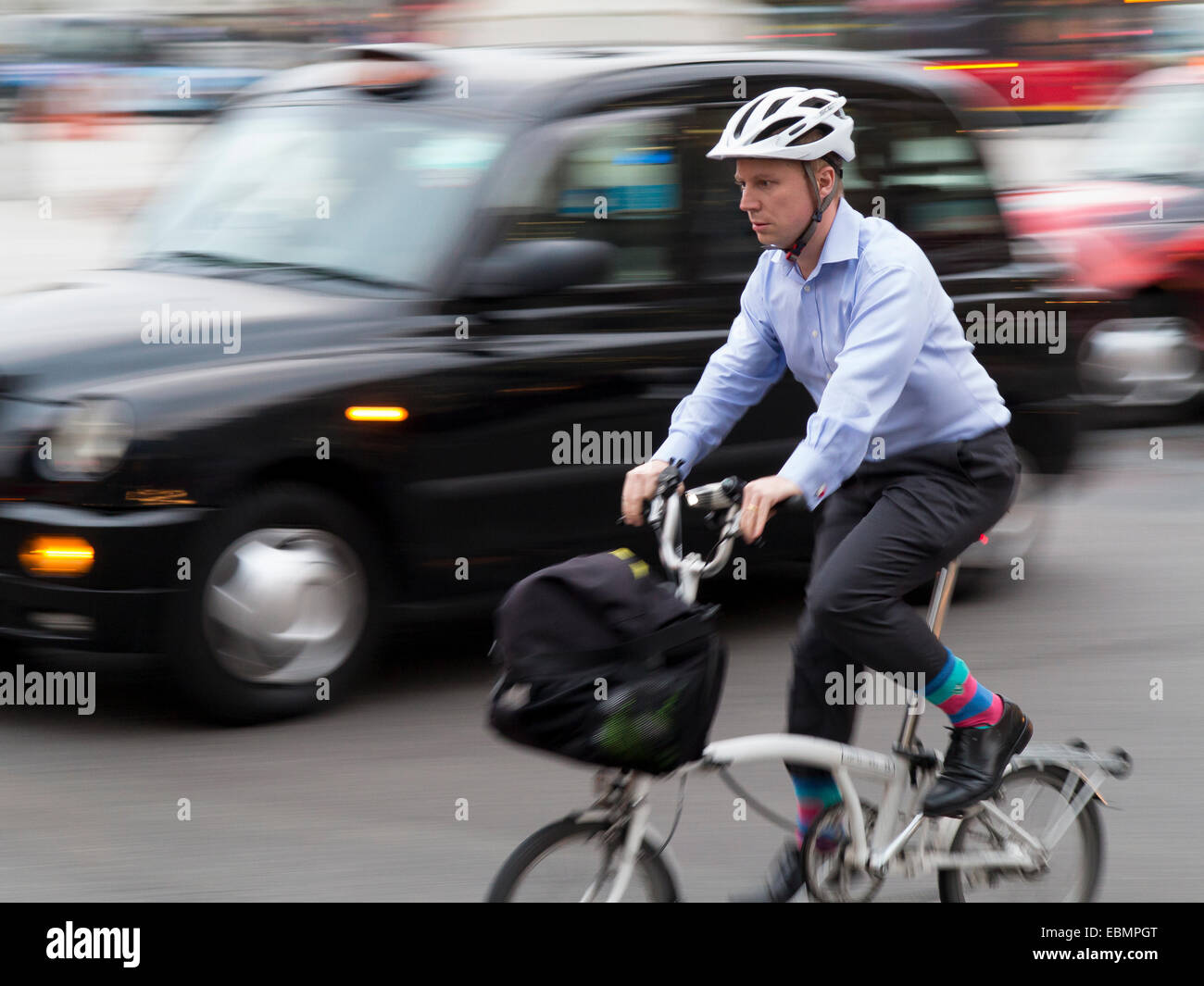 London, UK - October 23, 2014: A commuter cyclist wearing shirt and cufflinks negotiating the traffic of buses cars and taxis in Stock Photo