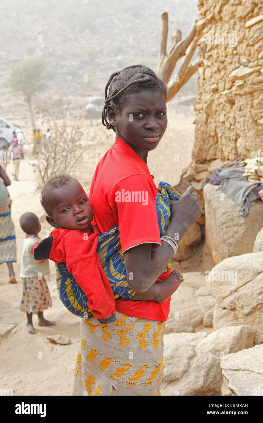 Woman of the Mafa ethnic group carrying a baby on her back, near Tourou, Far North, Cameroon Stock Photo