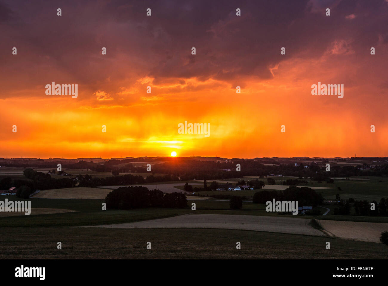 thunderstorm in front of setting sun and red evening sky, Germany, Bavaria, Isental Stock Photo