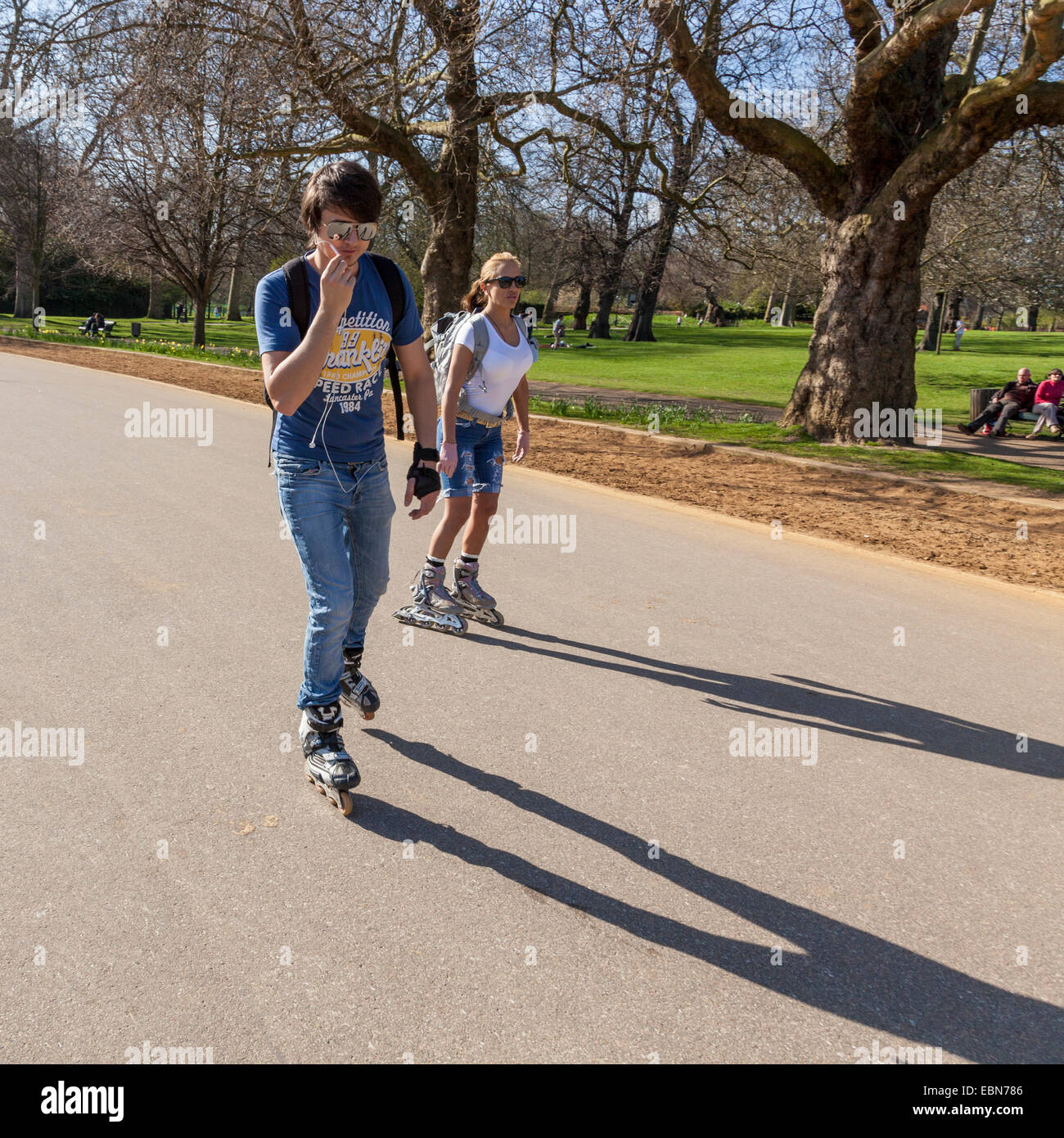 Two young people roller blading in Hyde Park, London, England, UK Stock Photo