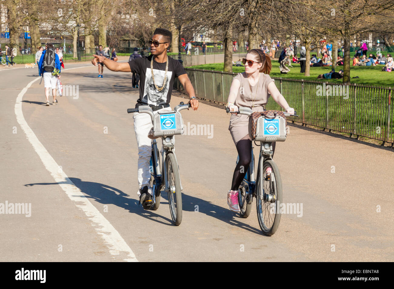 Two people cycling on Boris bikes in Hyde Park, London, England, UK Stock Photo