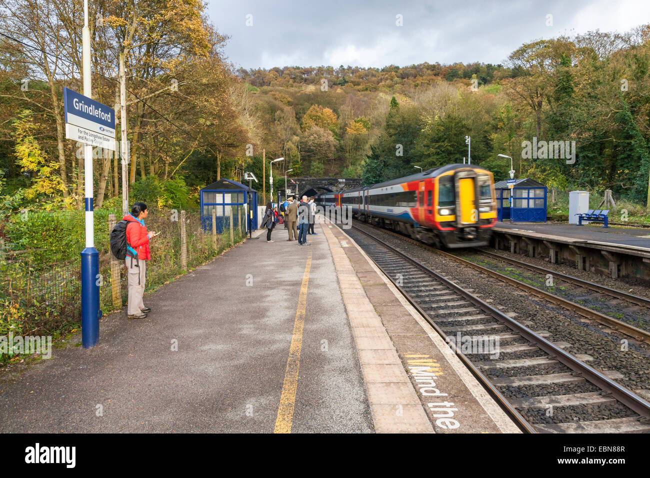East Midlands Trains train passing through the countryside railway station at Grindleford in the Peak District, Derbyshire, England, UK Stock Photo