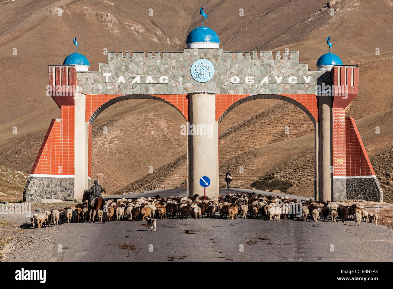 flock of sheeps on road with monument, Kyrgyzstan, Djalalabad, Taskoemuer Stock Photo