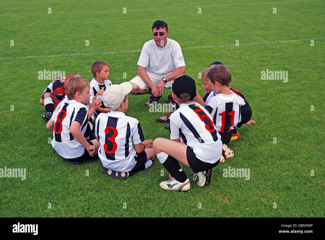 juvenile football coach at a tournament gathering his team in a circle on the lawn, Germany, Baden-Wuerttemberg Stock Photo