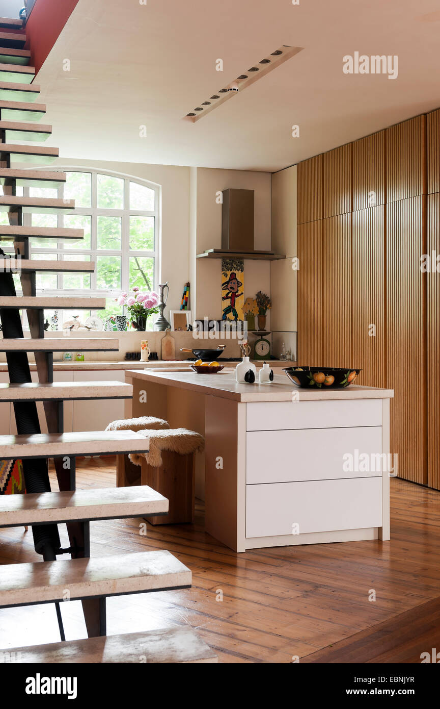 Open tread concrete stairs in kitchen with concrete work surfaces and wooden floors Stock Photo