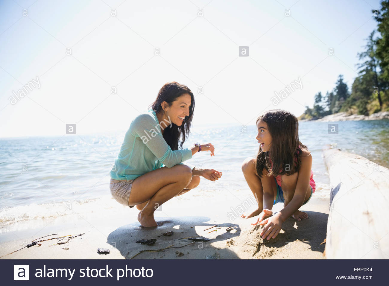 Mother and daughter clam digging on sunny beach Stock Photo