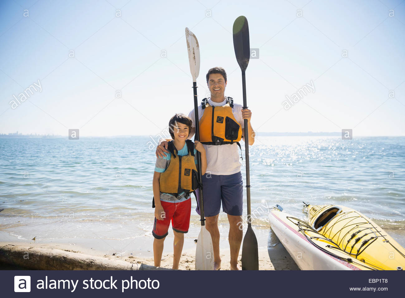 Father and son with kayaks on sunny beach Stock Photo