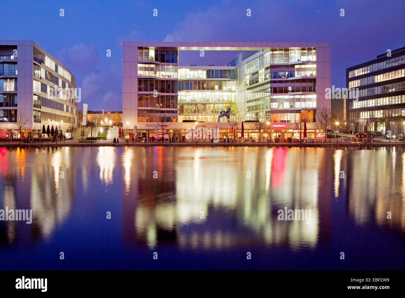 illuminated office buildings and gastronomy in harbour in the evening, Germany, North Rhine-Westphalia, Ruhr Area, Duisburg Stock Photo