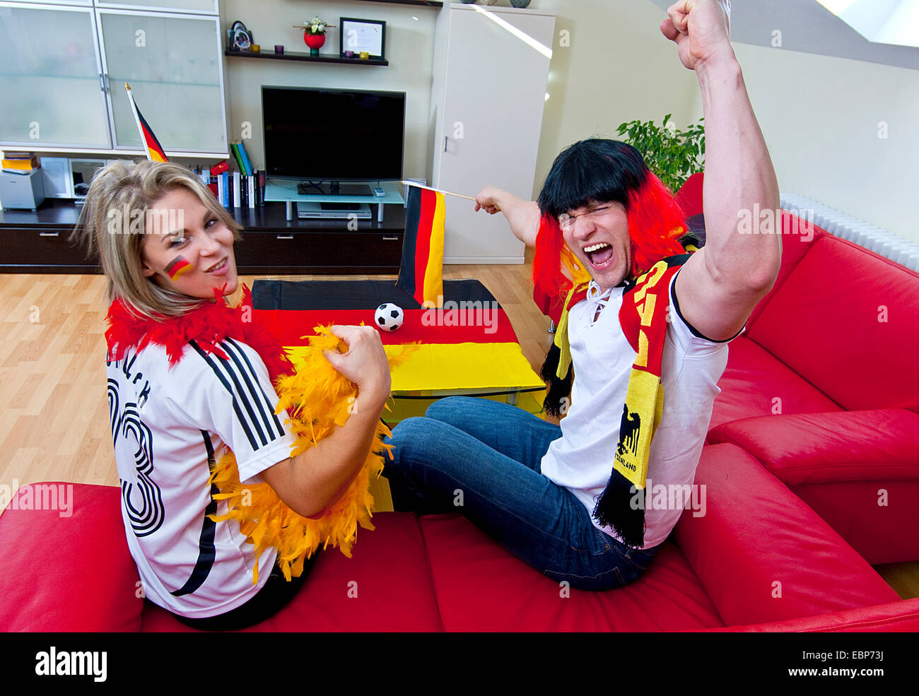 two soccer fans celebrating in living room, Germany Stock Photo