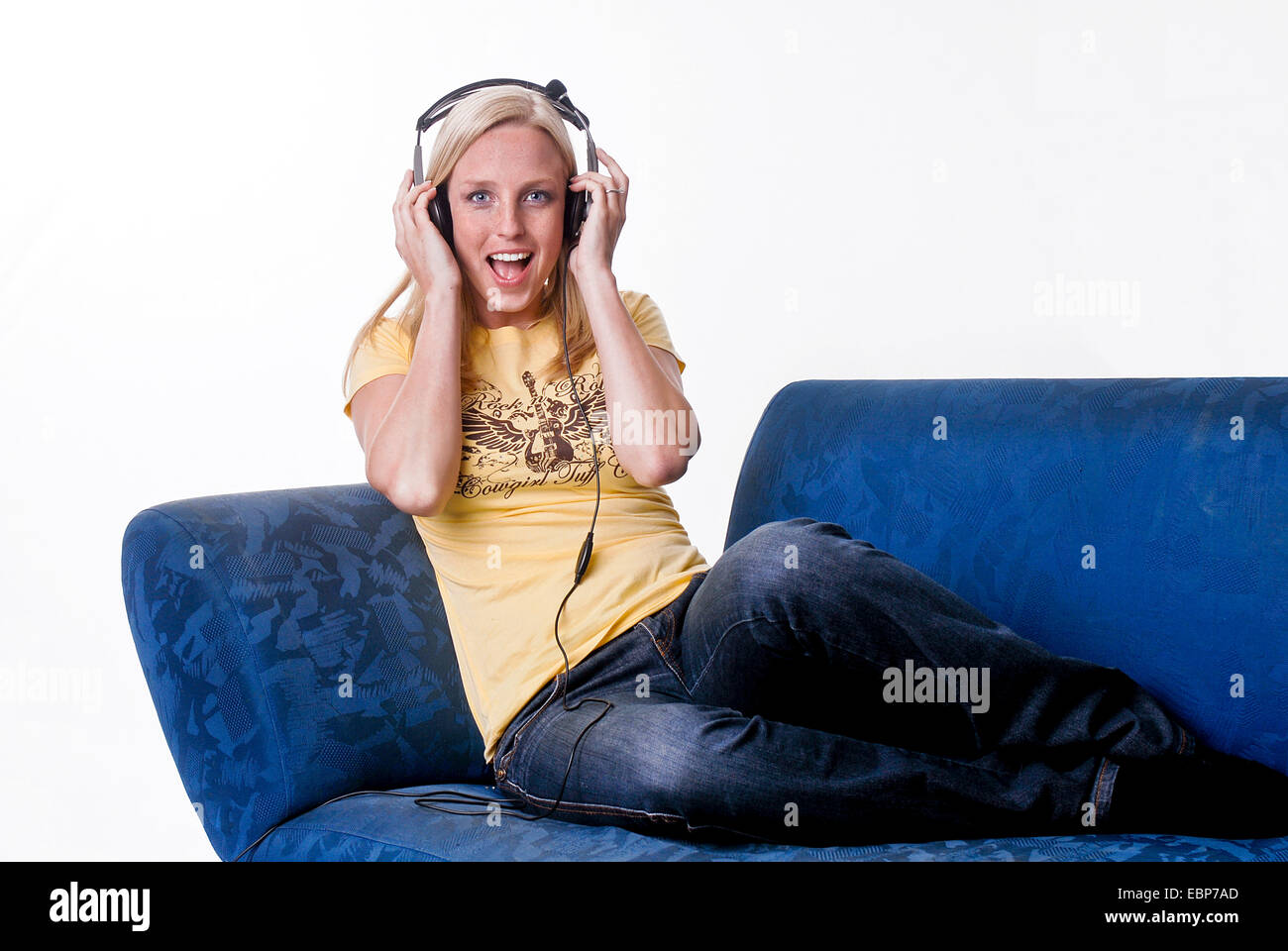 young woman sitting on a sofa listening to music Stock Photo - Alamy
