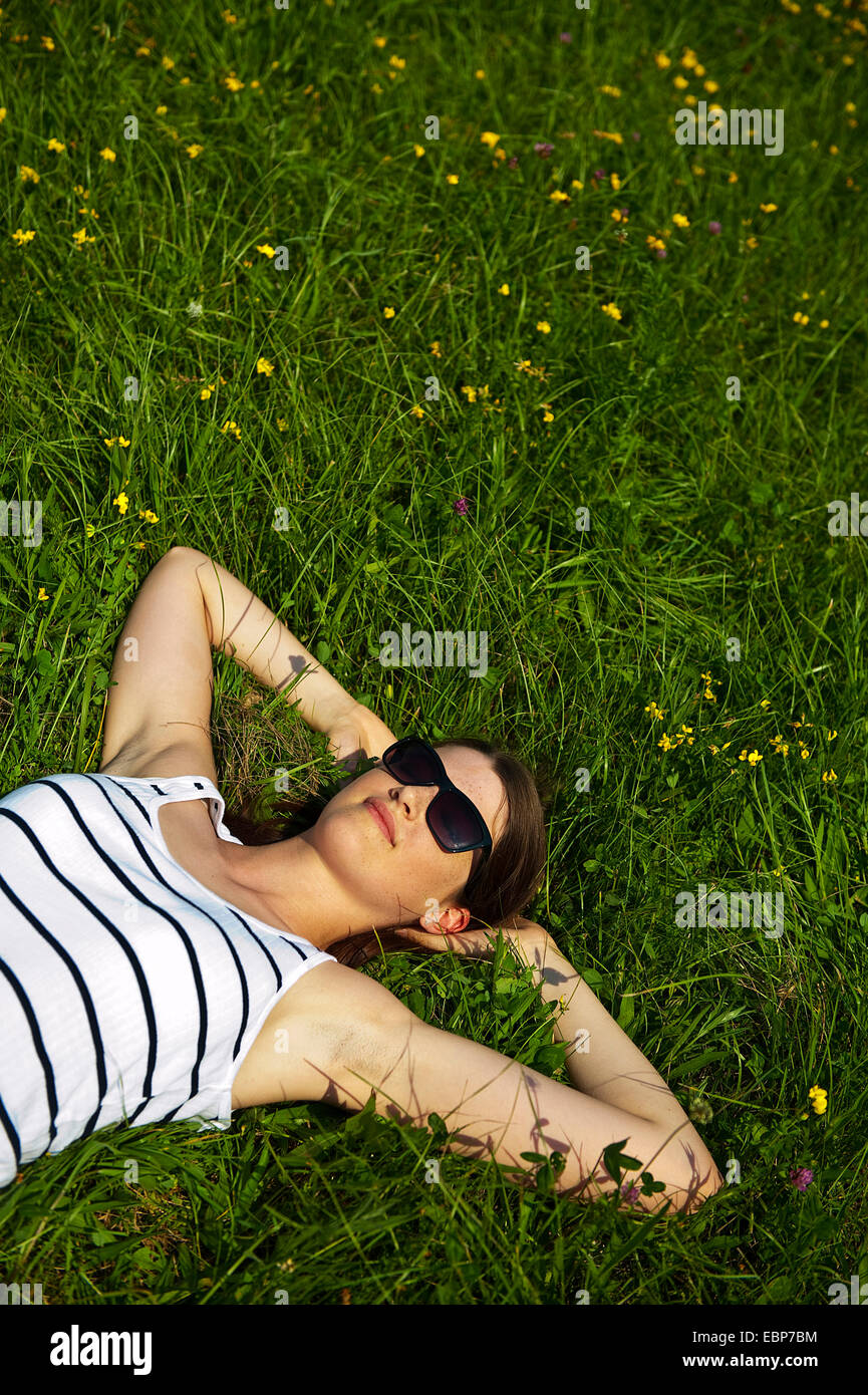 teenage girl with sunglasses lying in a meadow relaxing Stock Photo