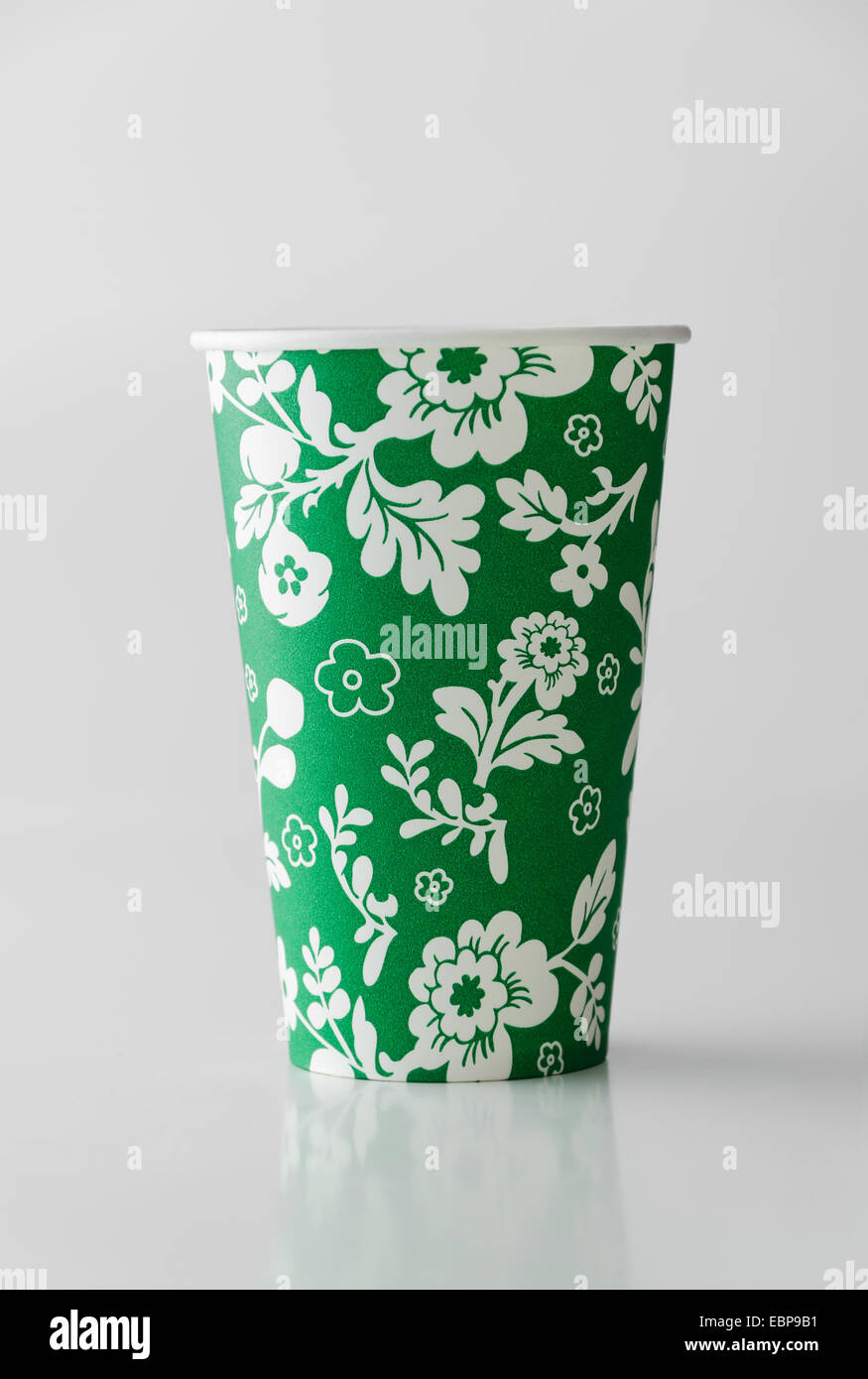Green paper cup with flowers pattern over white background Stock Photo