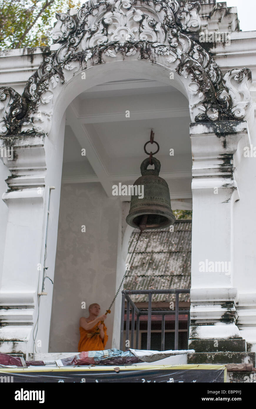 A Buddhist monk is ringing a bell in a bell tower at Wat Chedi Luang in Chiang Mai, Thailand Stock Photo
