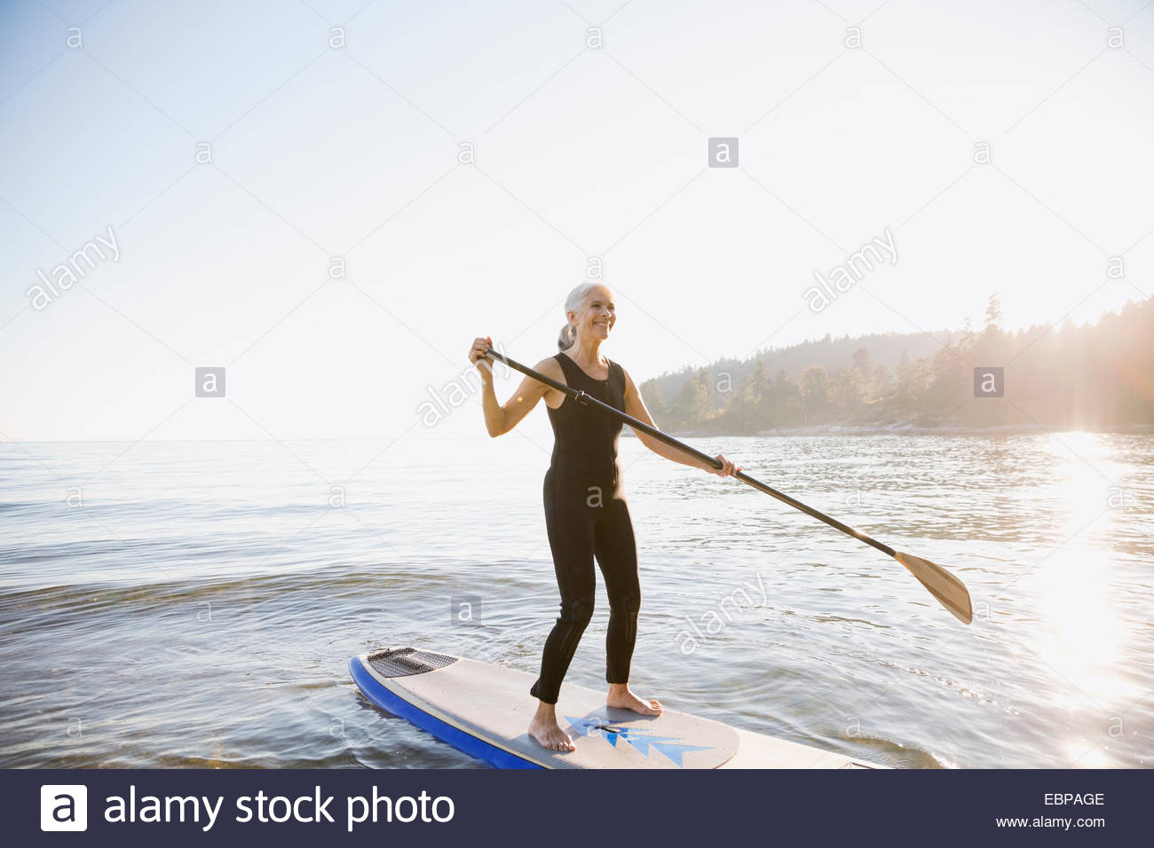 Senior woman paddle boarding in ocean Stock Photo Alamy