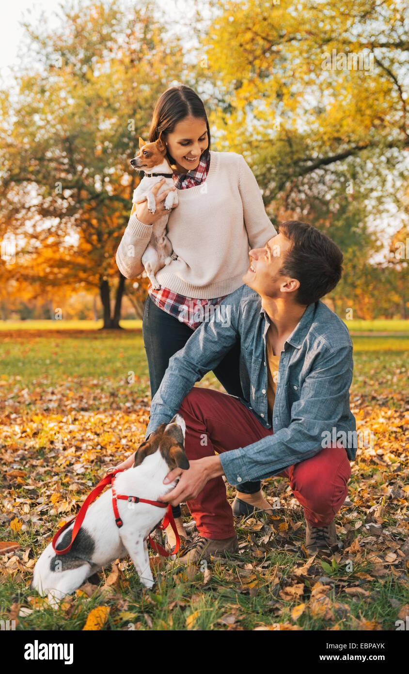 Happy young couple with dogs playing outdoors in autumn park Stock ...
