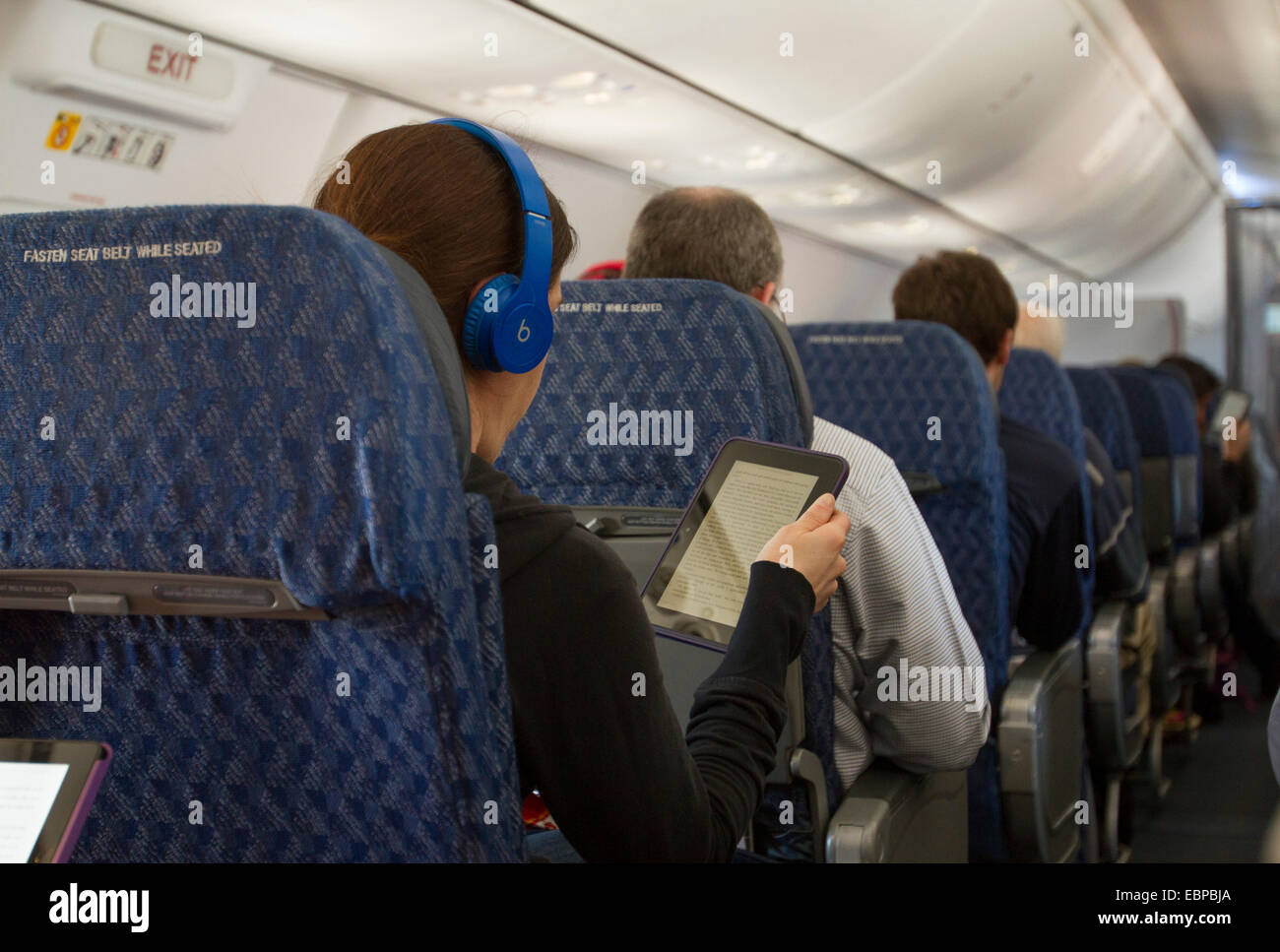 American Air;line passenger reading a tablet during a flight. Stock Photo