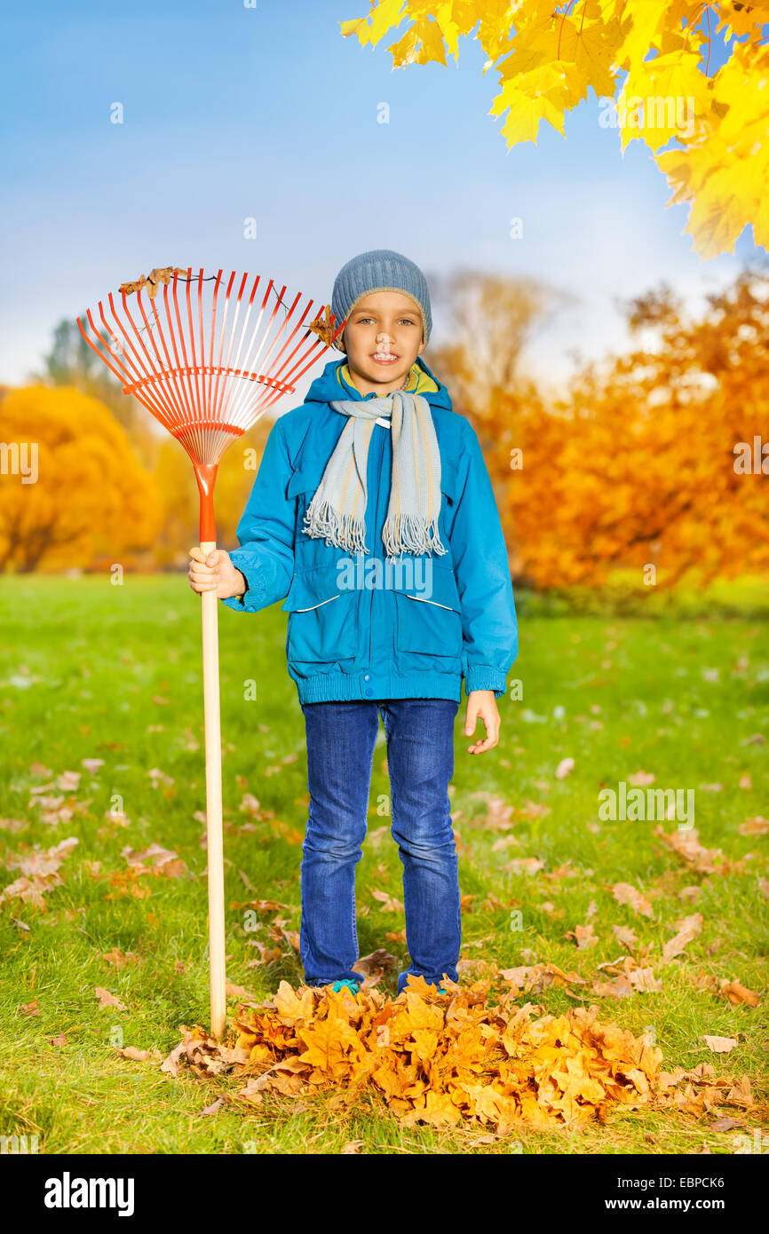 Cute small boy with rake stands to clean grass Stock Photo - Alamy