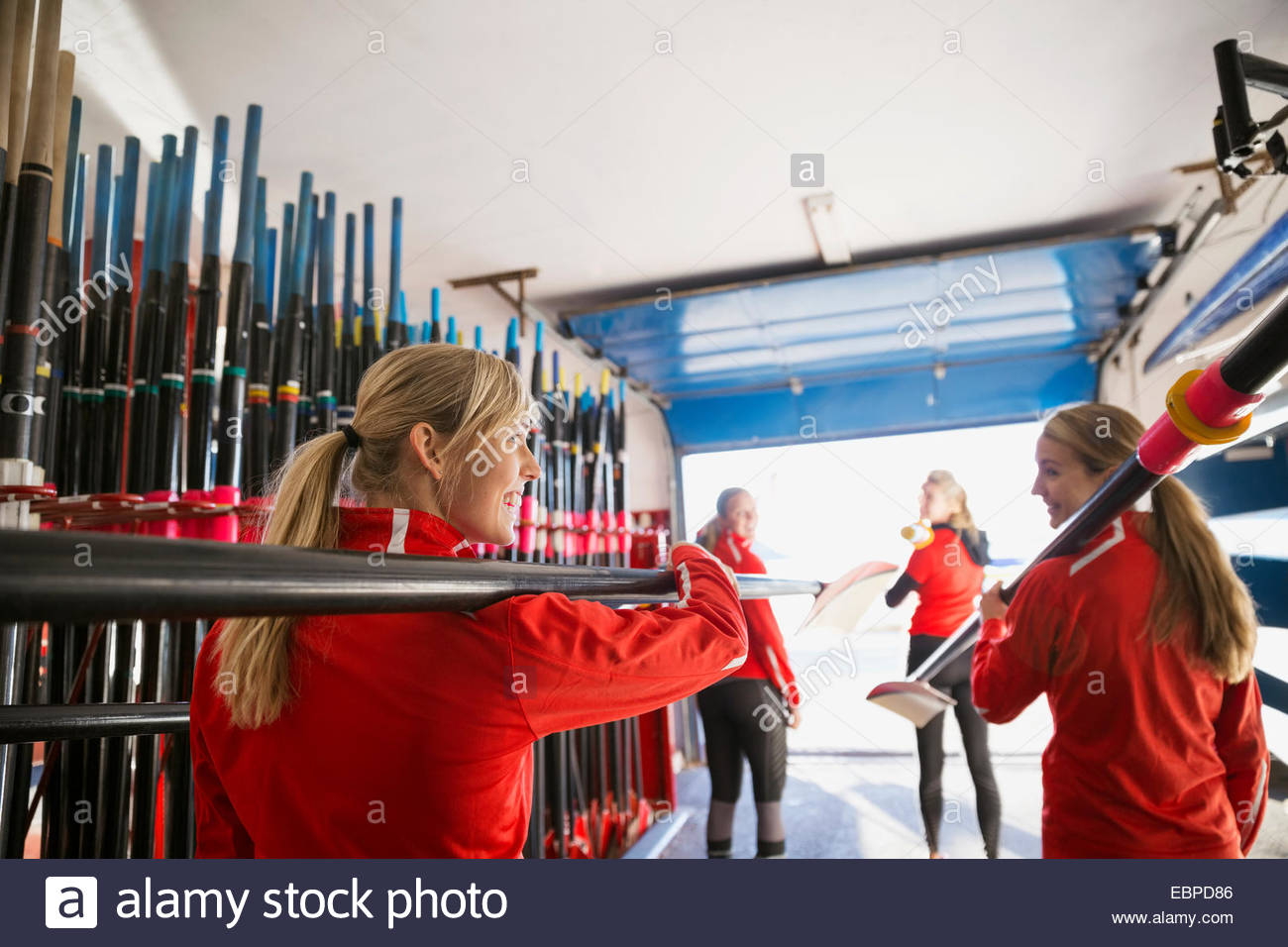 Rowing team carrying oars in boathouse Stock Photo Alamy