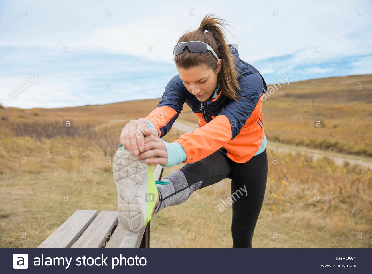 Runner stretching leg on rural bench Stock Photo