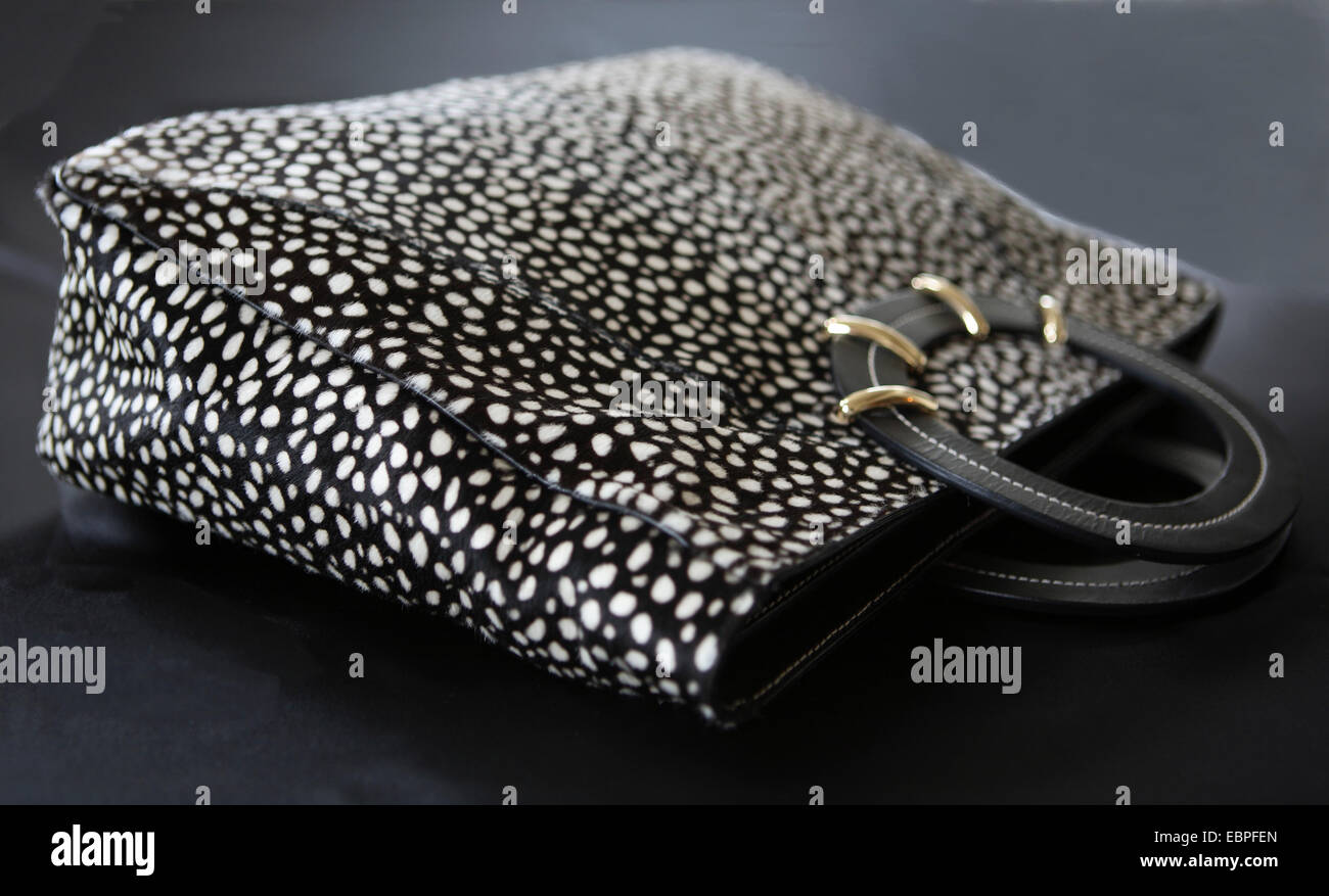 Pony hair black and white dot womens hand bag top handle with gold detail horizontal laying down Stock Photo