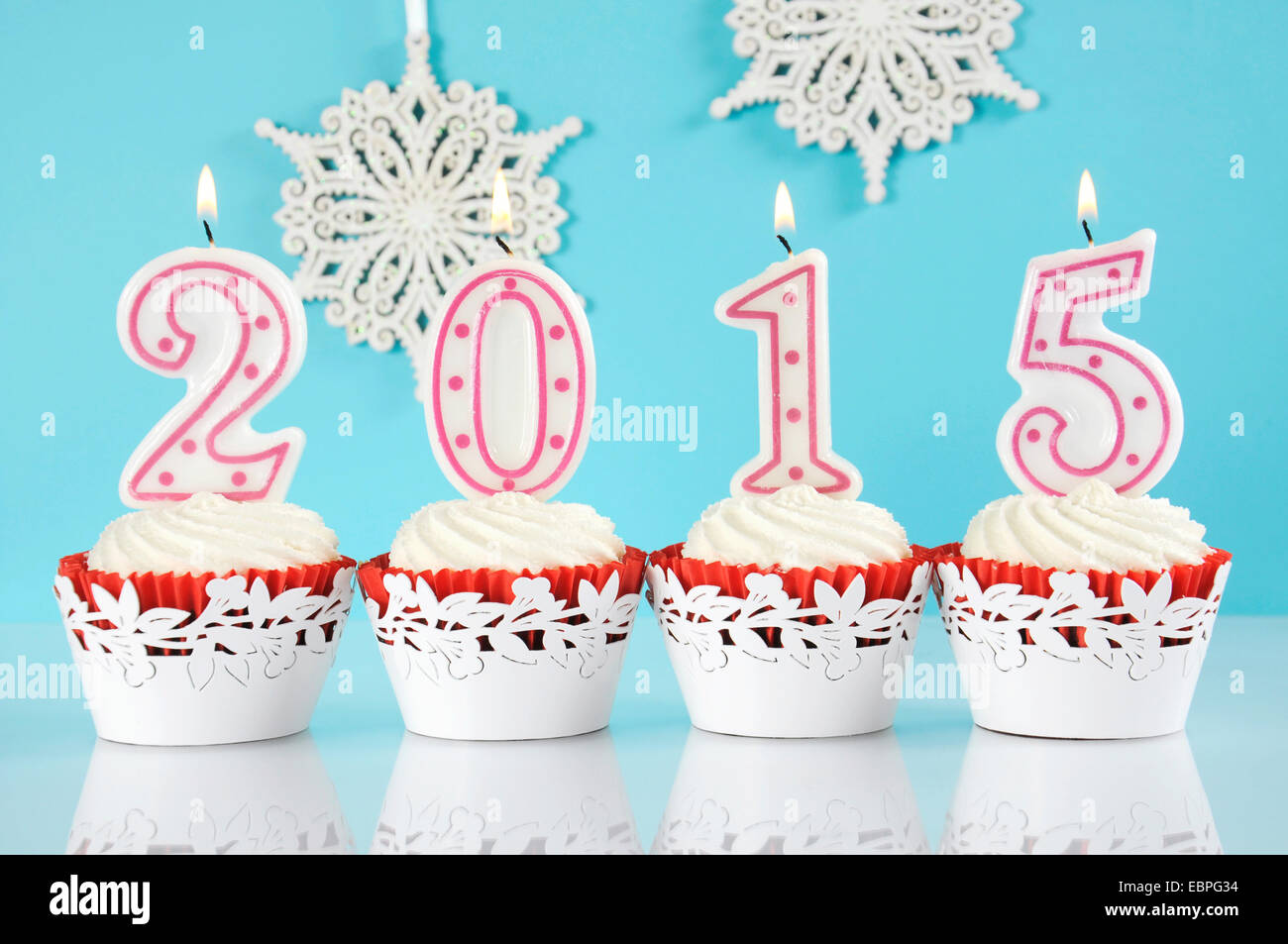 Happy New Year for 2015 red velvet cupcakes in red and white theme with lit candles and and snowflake decorations Stock Photo