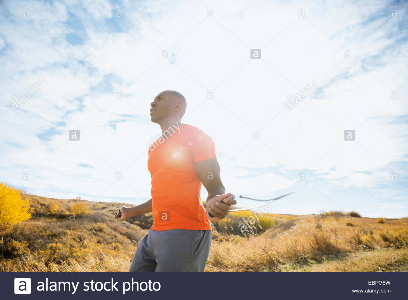 Man jump roping in rural field Stock Photo
