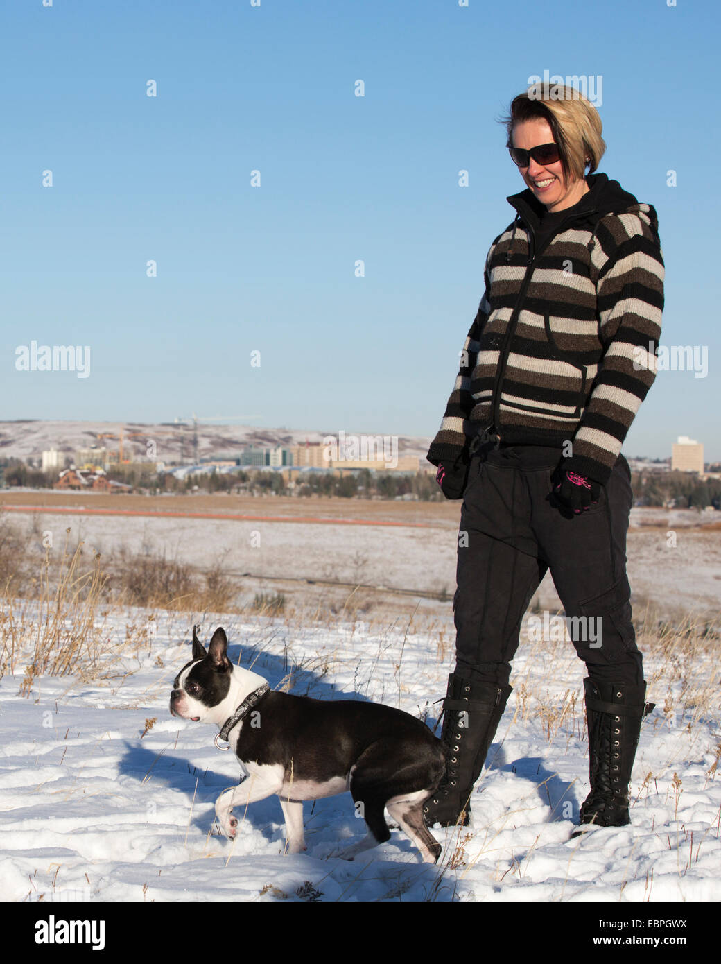 Woman and her Boston Terrier dog enjoying walking in nature outside in city park Stock Photo