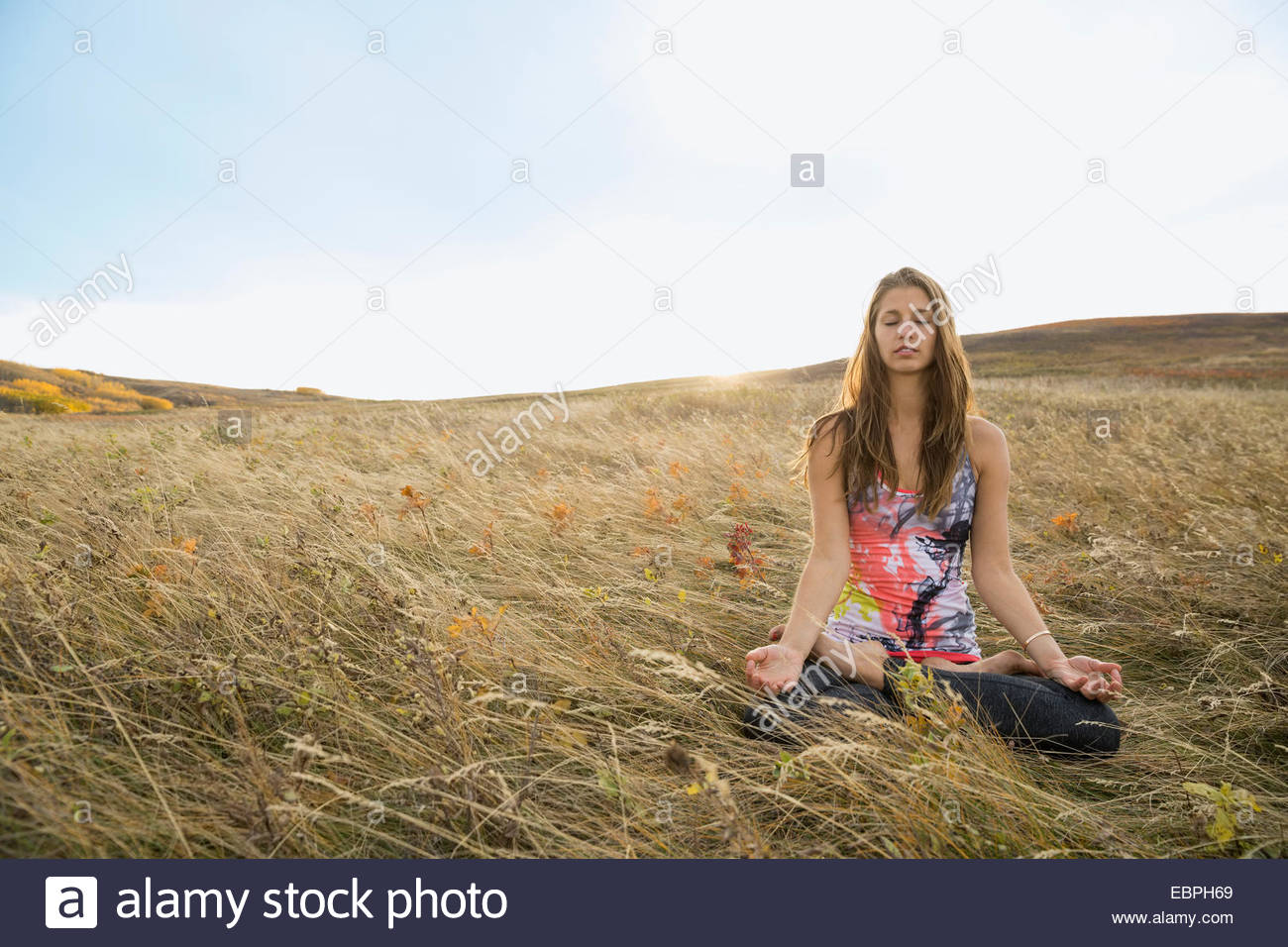 Serene woman meditating in rural field Stock Photo