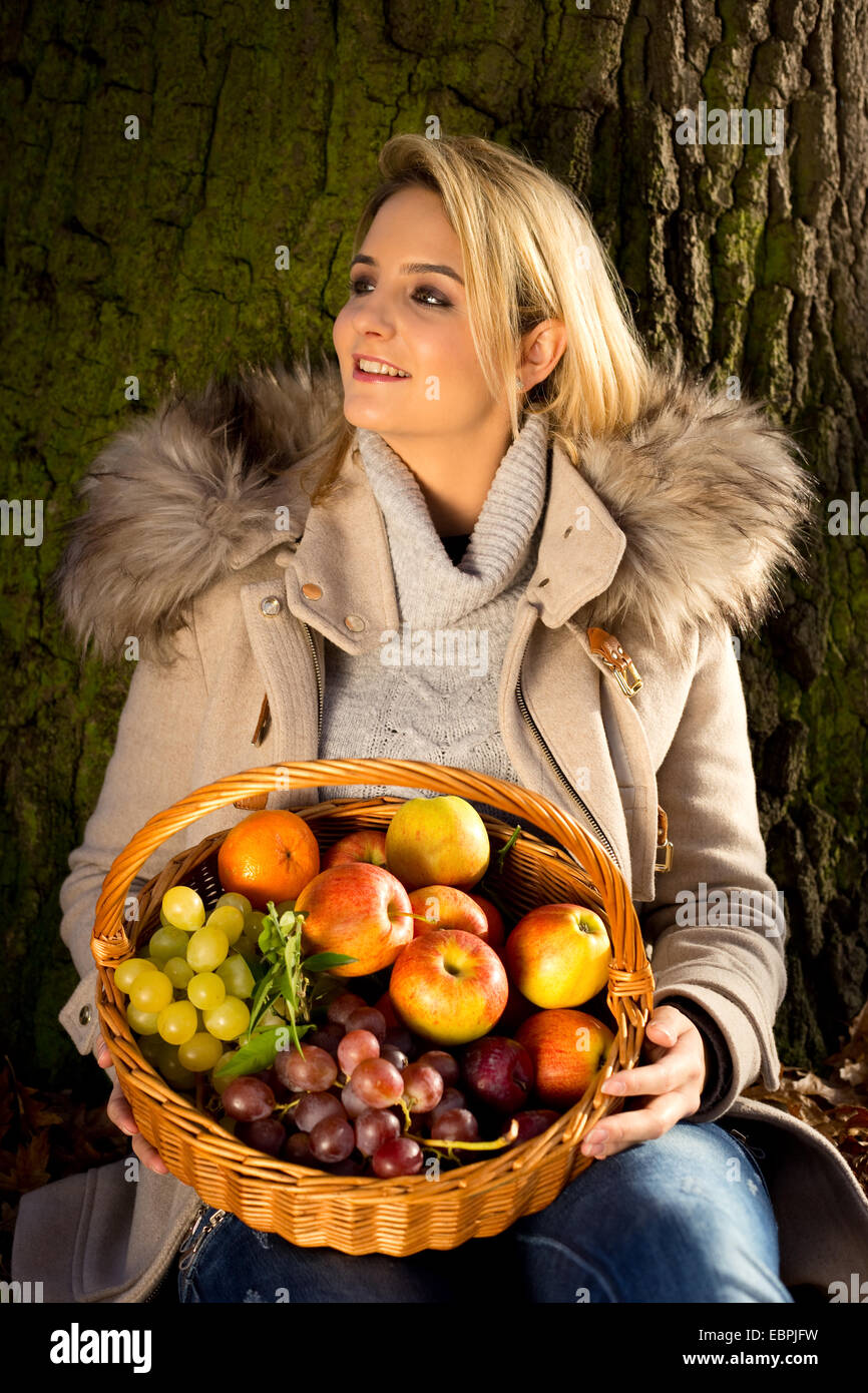 young woman sitting in a park with a basket of fruit Stock Photo - Alamy