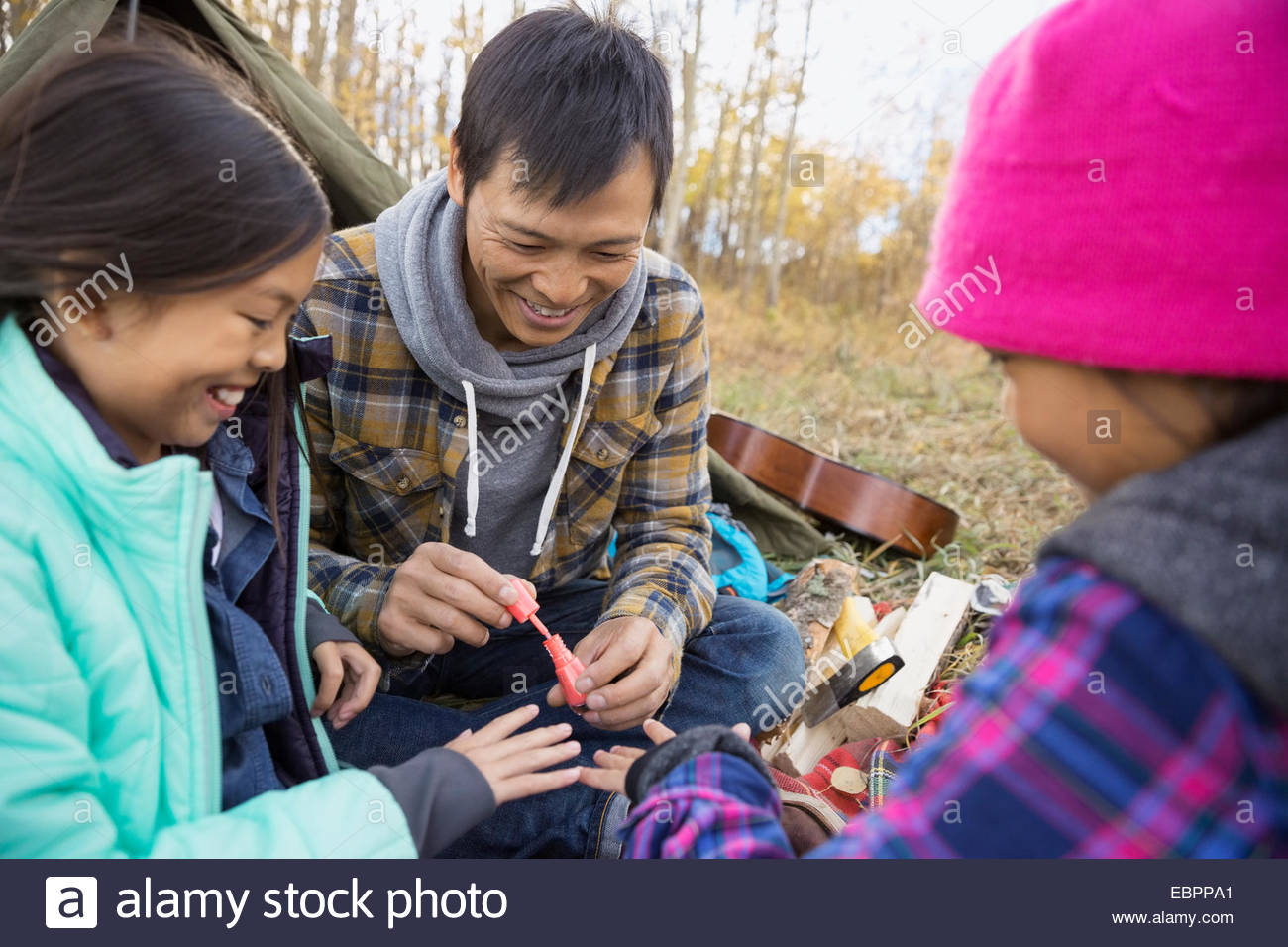 Father giving daughter manicure at campsite Stock Photo