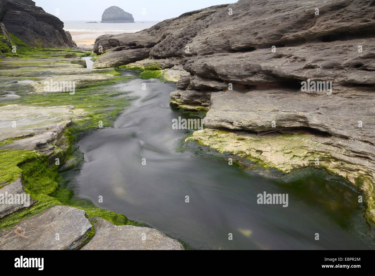 Freshwater stream carving through soft volcanic rocks to reach the sea, Trebarwith Strand, Cornwall, England, United Kingdom Stock Photo