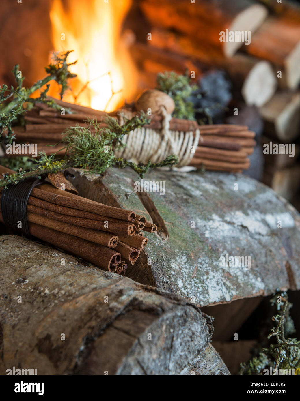 Bundles of cinnamon sticks and logs in basket by the fire Stock Photo