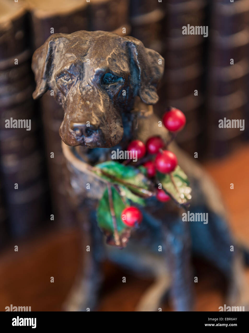 A sprig of holly adds a festive touch to a smal bronze dog statue Stock Photo