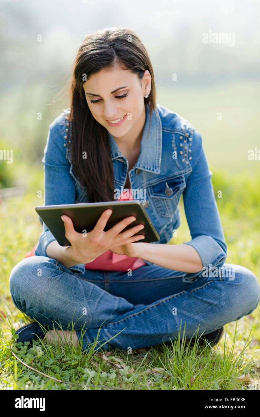 young woman with IPad in tailor seat in a meadow Stock Photo