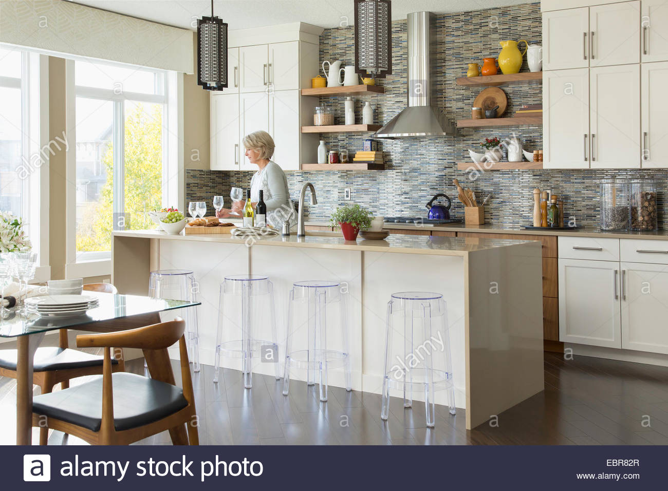 Woman with wine glasses in kitchen Stock Photo