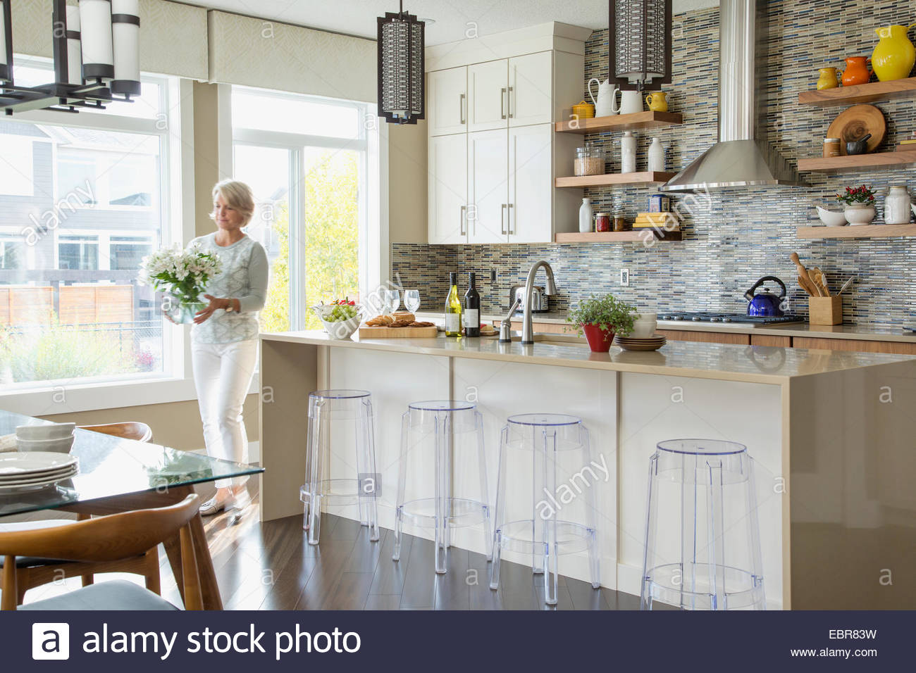 Woman carrying bouquet of flowers in kitchen Stock Photo